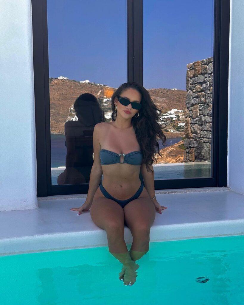 Madison Pettis sits on the edge of the pool.